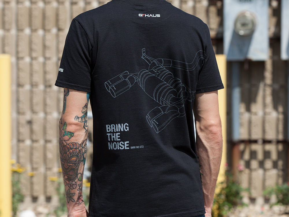 Black MEISTERSCHAFT T-shirt featuring a graphic of a BMW M3 exhaust system and the phrase "BRING THE NOISE" on the back.