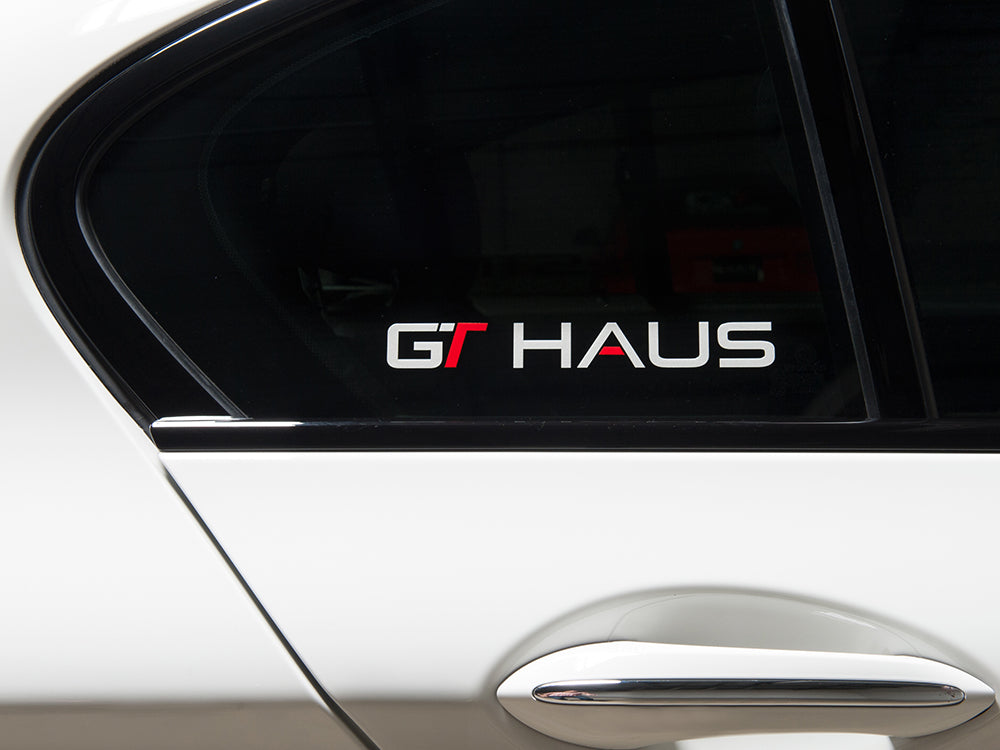 GTHAUS decal displayed on a car window, featuring a bold design with the text GT HAUS in red and white.