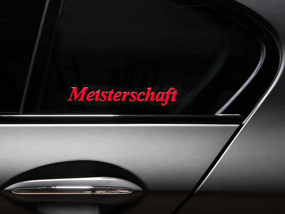 Meisterschaft decal with transparent background displayed on a car window, showcasing bold red lettering.