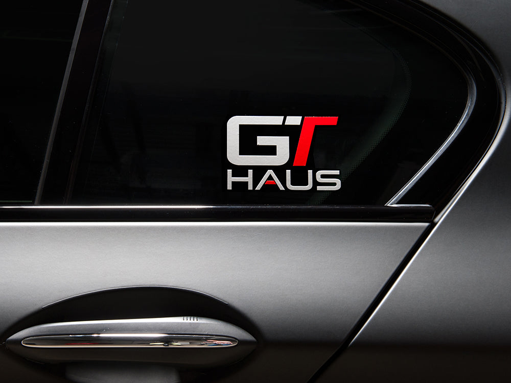 GTHAUS decal displayed on a car window, featuring a sleek design with red and silver lettering.