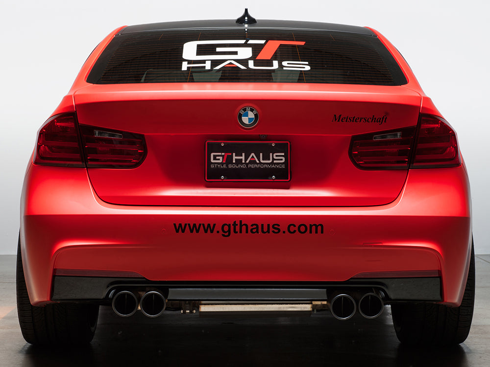 Meisterschaft license frame and GTHAUS license plate on a red BMW, showcasing premium performance branding.