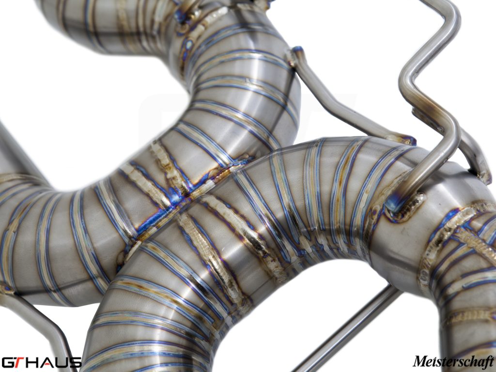 Close-up of a hand-welded stainless steel exhaust system for BMW E90/92/93 M3, showcasing precision craftsmanship and design.